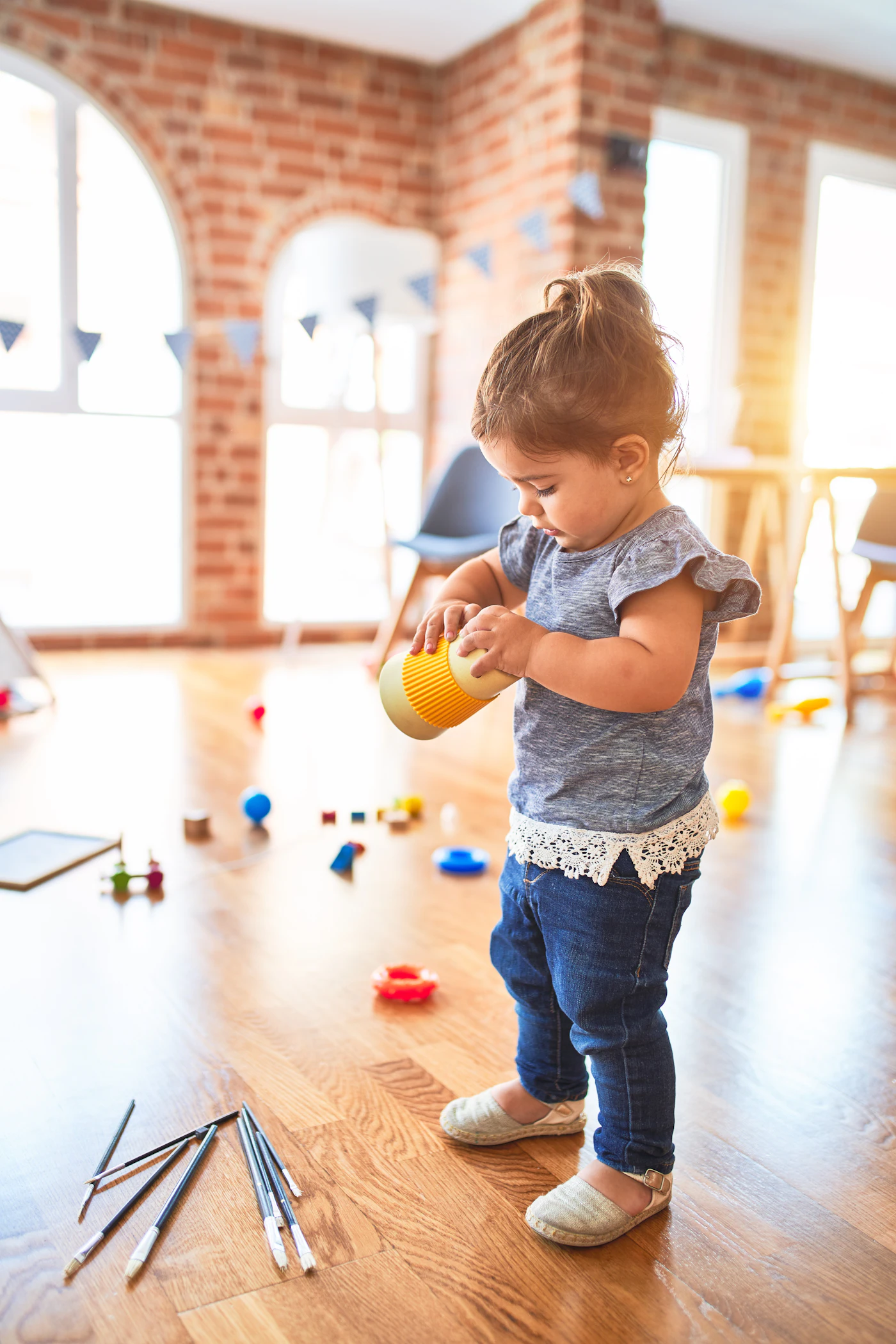 Une petite fille joue dans une salle lumineuse au parquet clair